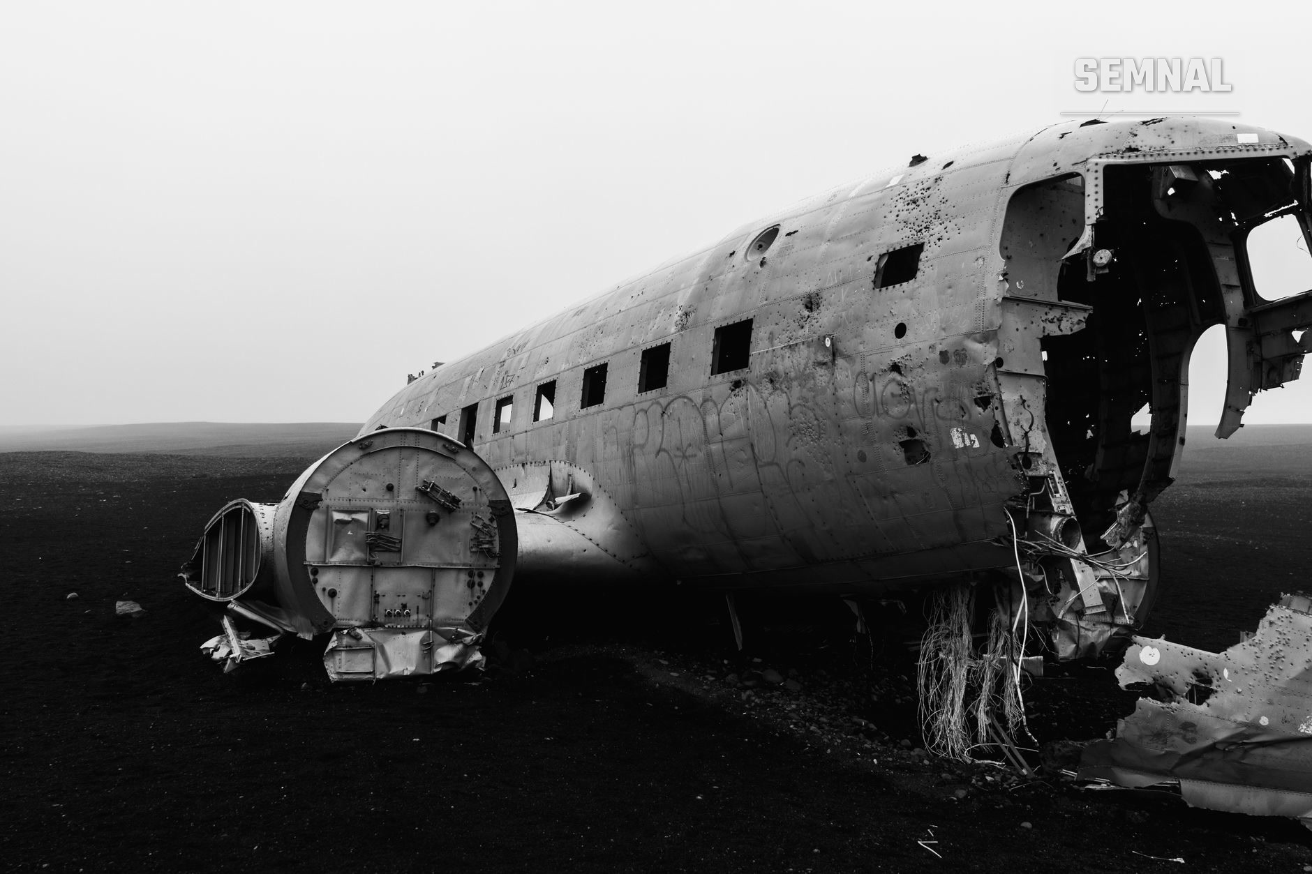 Rămășițe ale avionului Pam Am Flight 103 după atentatul de la Lockerbie din 1988, cu fuselaj sfărâmat și structură metalică expusă, într-o fotografie alb-negru care documentează catastrofa aeriană.