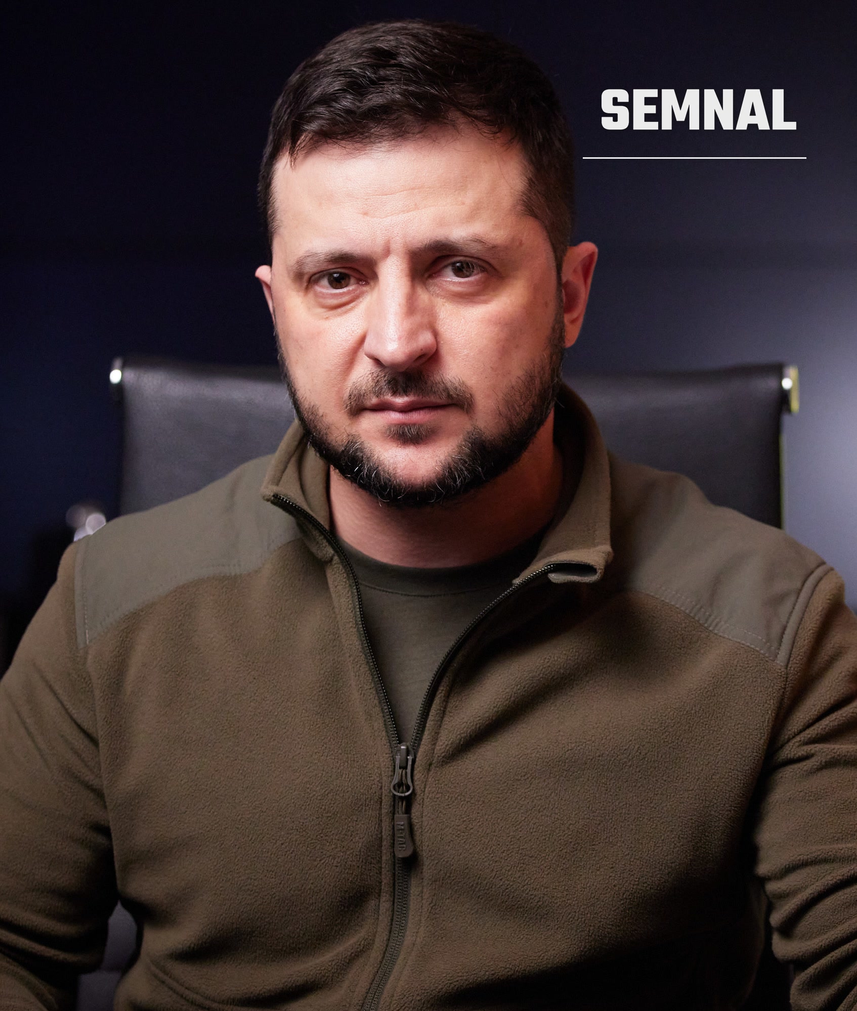 Volodimir Zelenski, președintele Ucrainei, portretu frontal într-o jachetă kaki, cu expresie serioasă în fața unui fond negru (Foto: President of Ukraine from Україна)