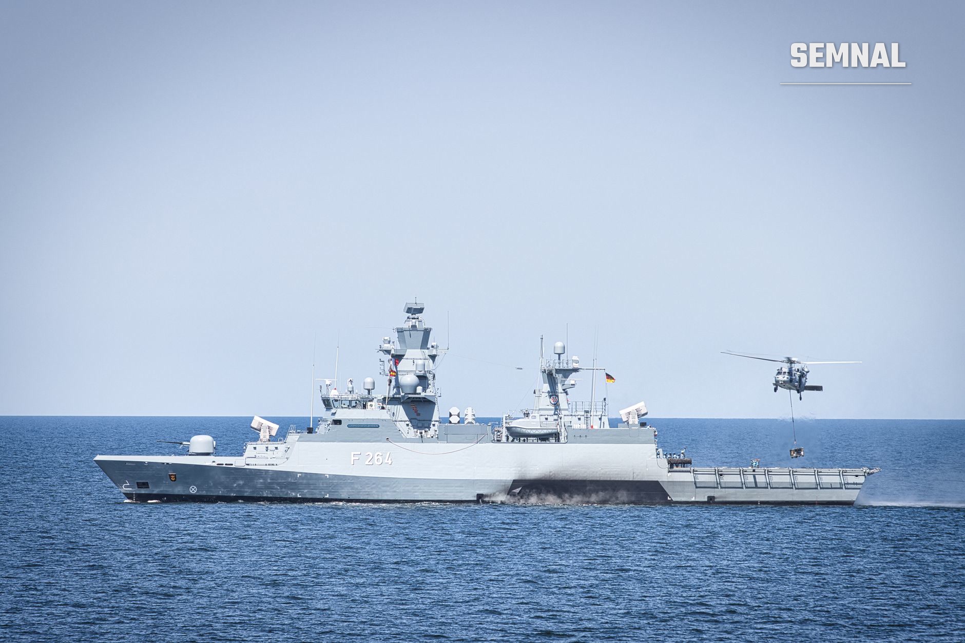 Fregată militară gri cu numărul F264 pe carcasă, dotată cu radare și sisteme de comunicații, navigând în apă albastră, cu elicopter militar vizibil în dreapta imaginii. (Foto: Germannavyphotograph / Pexels)