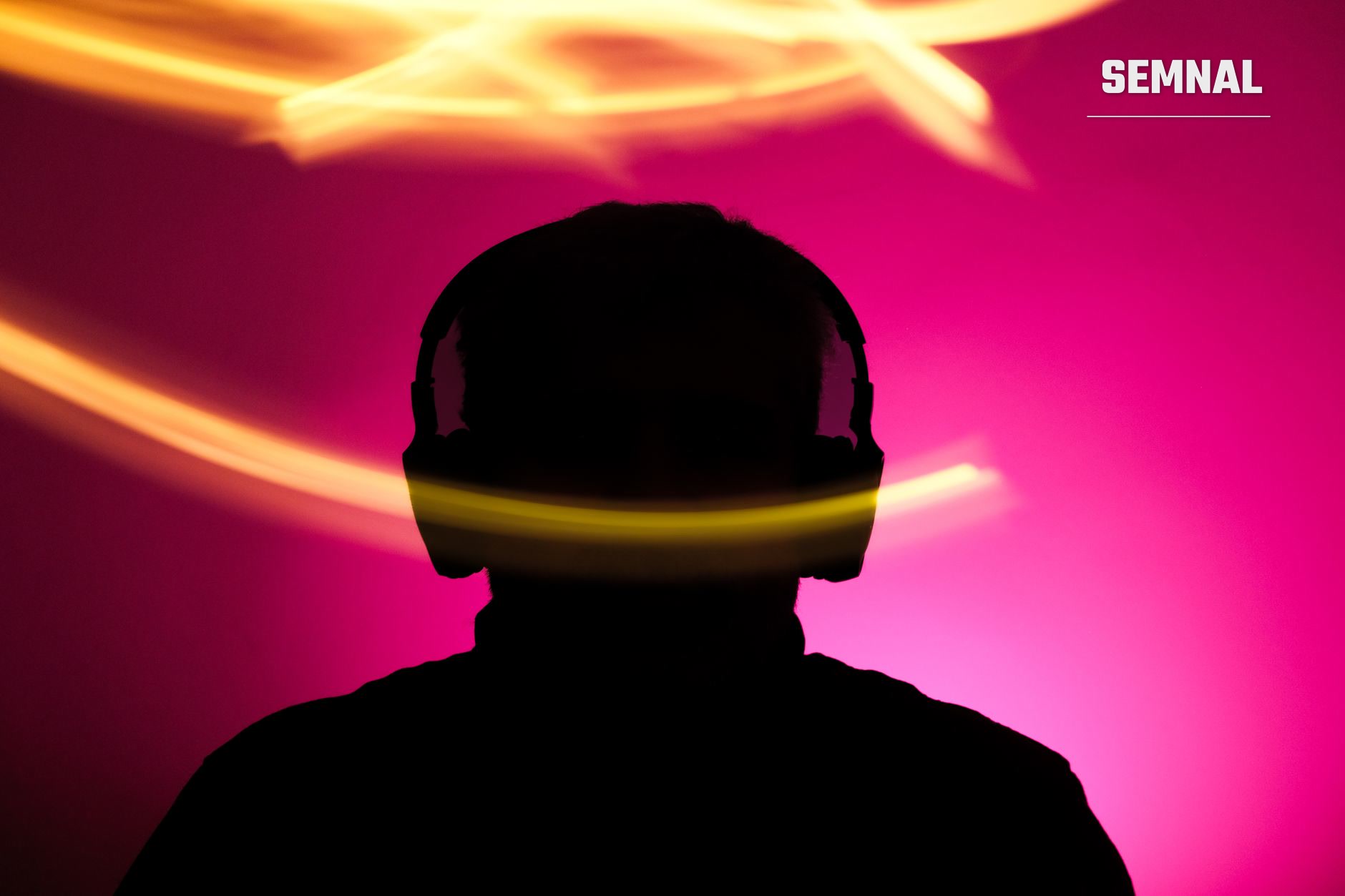 Silueta unui cap uman cu o bandă luminoasă galbenă peste ochi, pe fundal gradient magenta și portocaliu, reprezentând sinestezia și cross-sensingul senzorial. (Foto: Beyzaa Yurtkuran / Pexels)