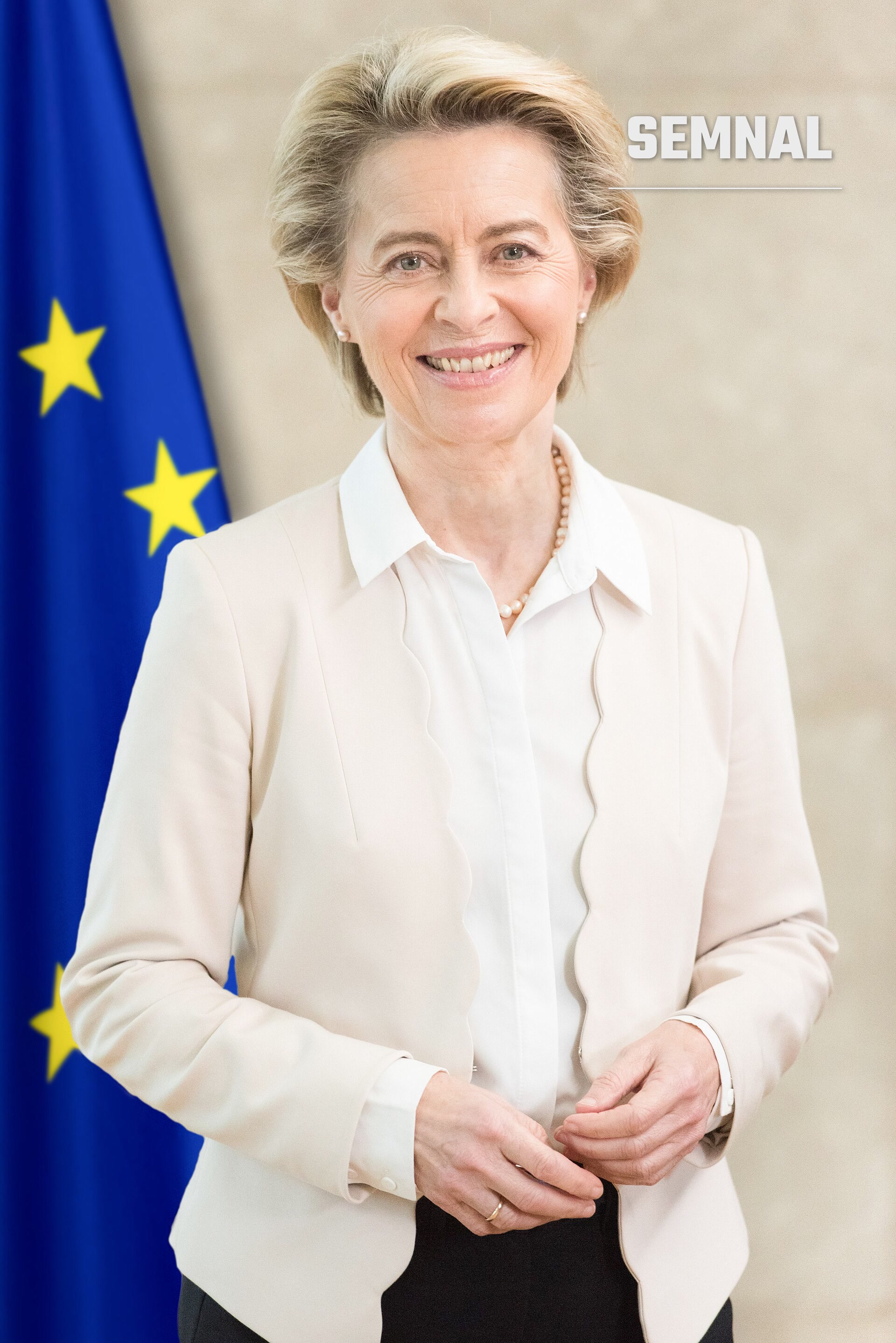Ursula von der Leyen, președinta Comisiei Europene, în portret oficial cu blazer crem și colier de perle, zâmbind la cameră, cu steagul UE în fundal. (Foto: Etienne Ansotte, © European Union, 2021)