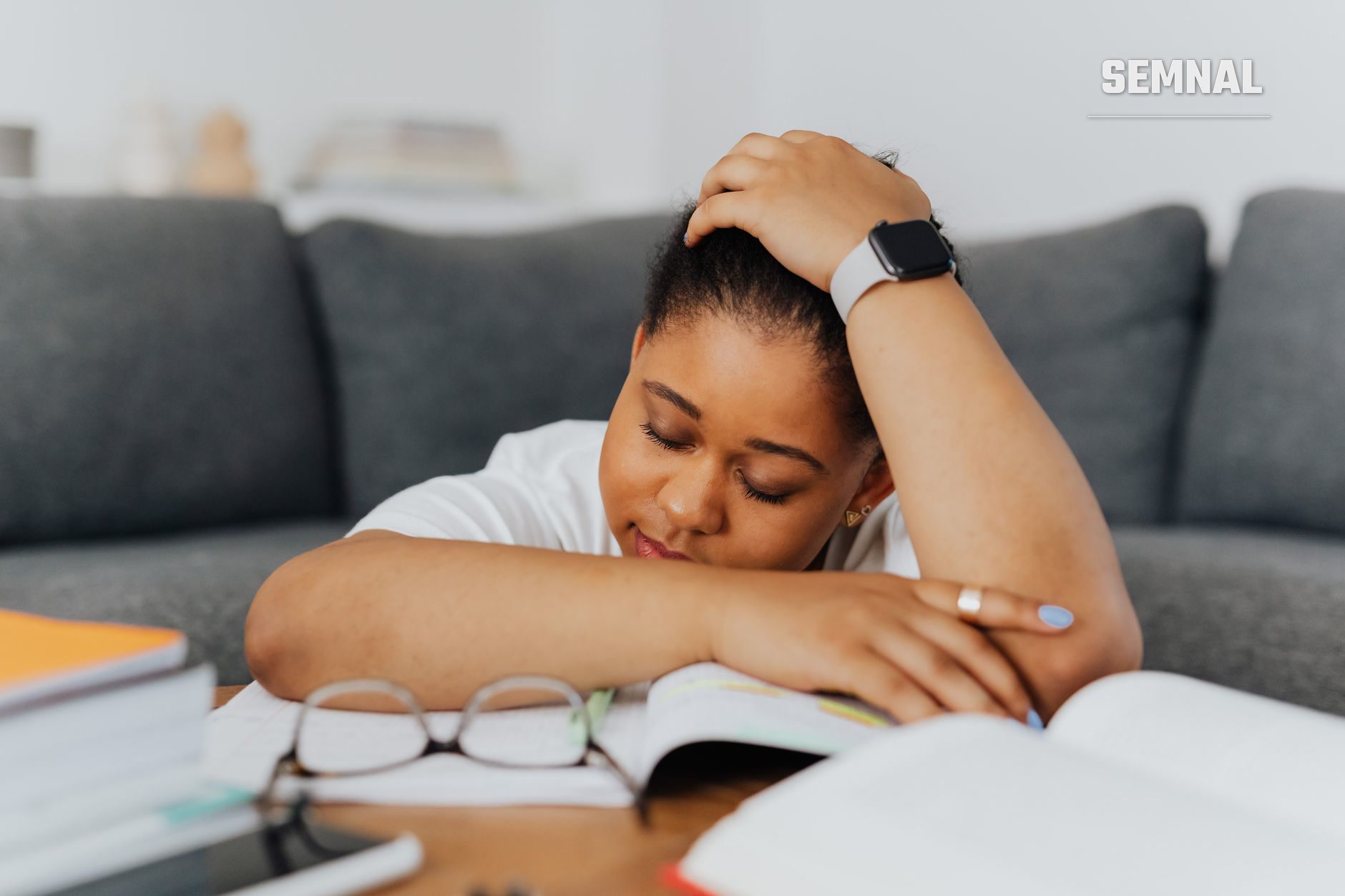 Femeie obosită sprijinind capul în mână la o masă de lucru, purtând smartwatch, cu expresie de epuizare și oboseală cronică. (Foto: https://kaboompics.com/ / Pexels)