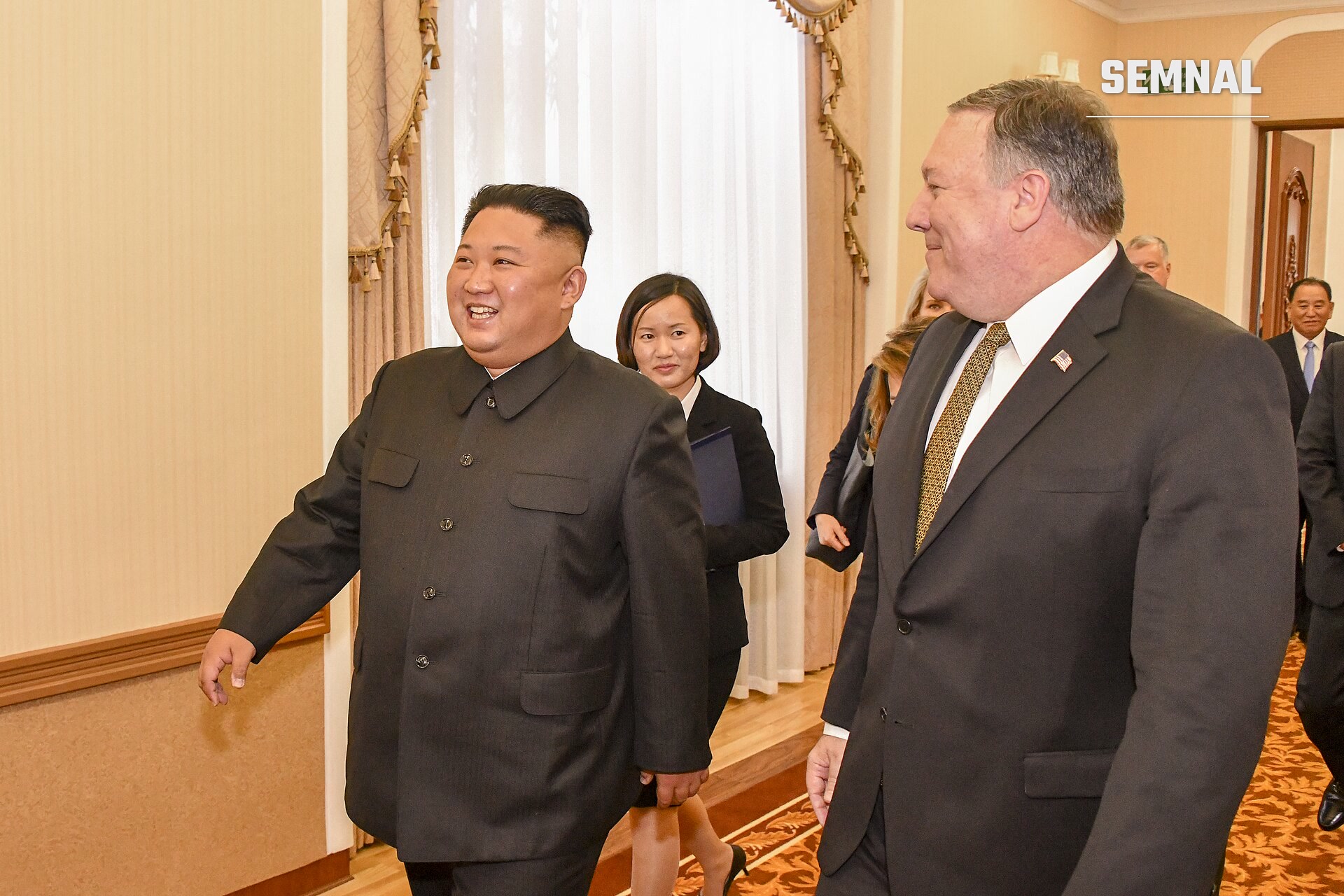 Kim Jong-un, în costum militar negru, se află în prim-plan la o întâlnire oficială în interior, într-o sală elegant decorată cu draperii și ornamente aurii. (Foto: U.S. Department of State from United States)