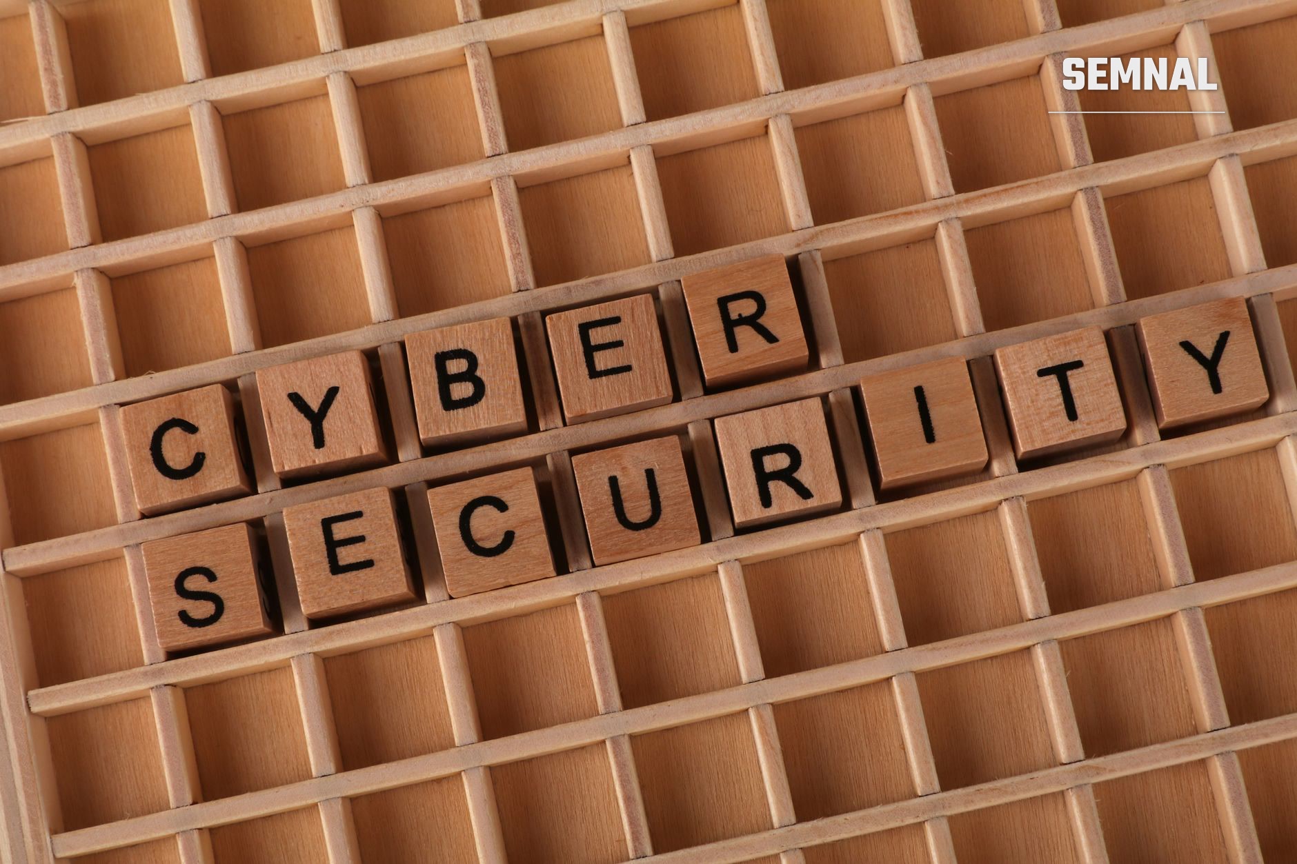 Cuburi de lemn cu litere formând cuvintele 'CYBER SECURITY' aranjate într-o cutie de sortare din lemn, simbolizând protecția datelor și securitatea cibernetică. (Foto: Ann H / Pexels)