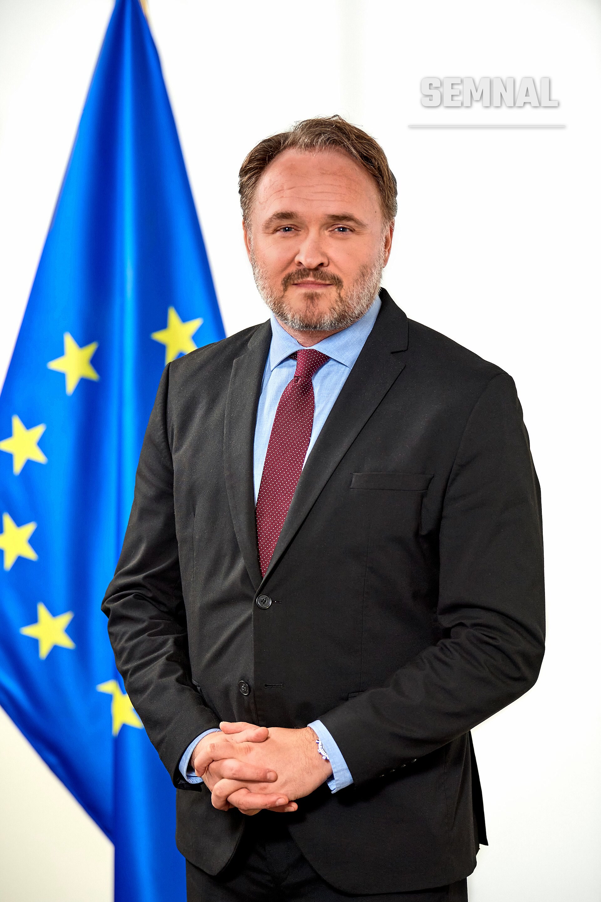 Dan Jørgensen, comisarul european pentru energie, în portret oficial în fața drapelului UE, îmbrăcat în costum negru și cravată roșu-burgundy. (Foto: European Commission Audiovisual Service)