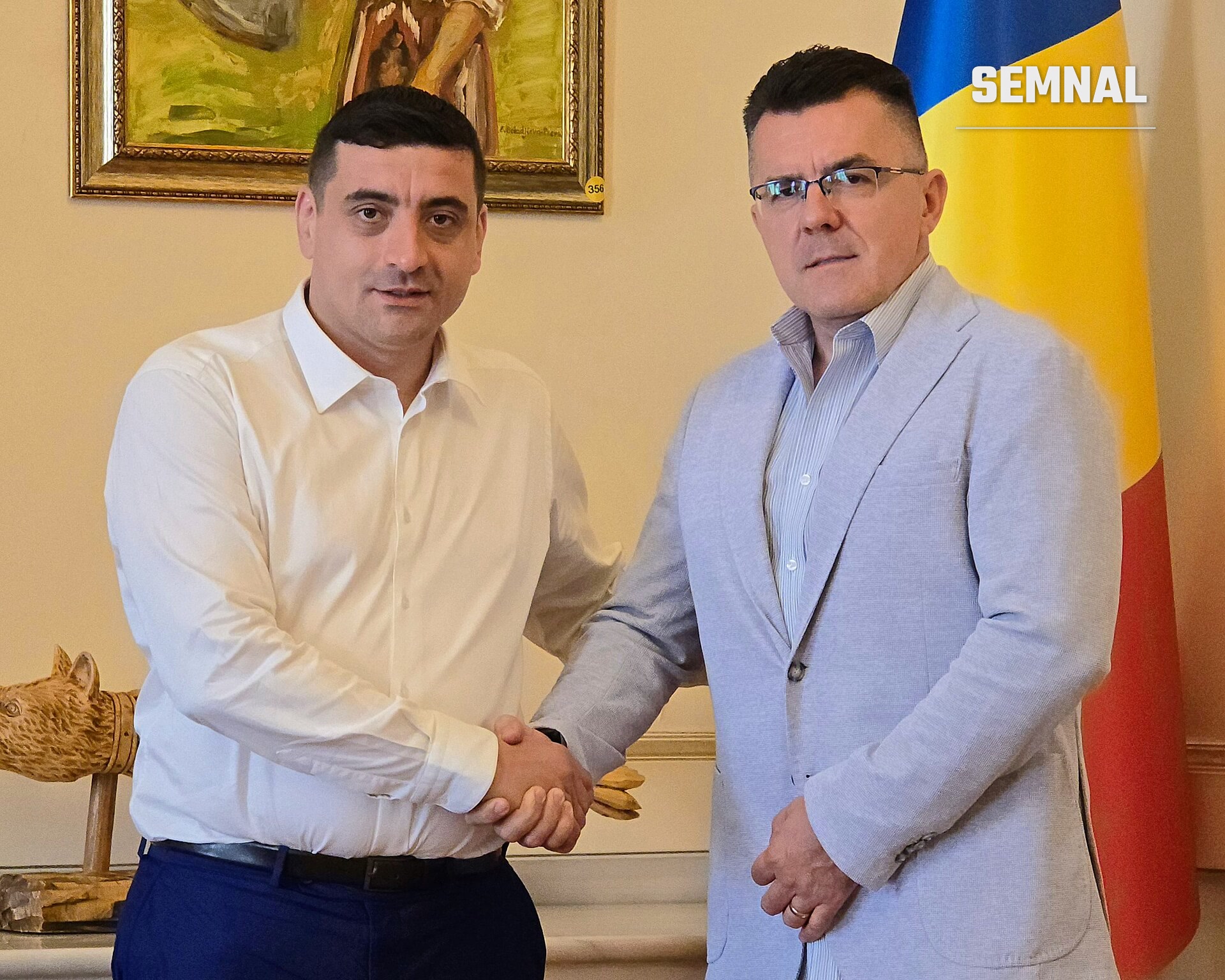 George Simion, președintele AUR, strângând mâna cu un alt oficial într-o sală oficială, cu steagul României în fundal. (Foto: AUR Alianța pentru Unirea Românilor)