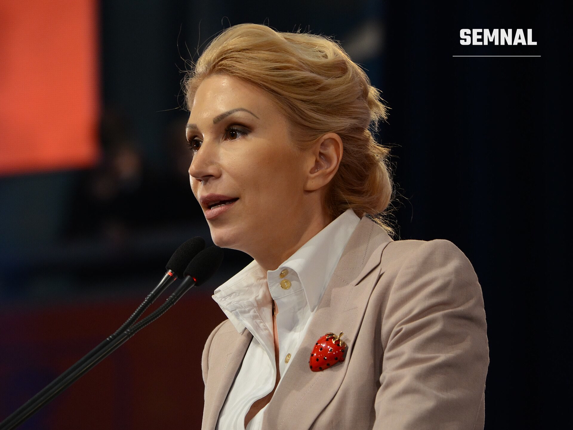 Raluca Turcan, deputată, vorbind la microfoane într-o conferință de presă, purtând haină bej și cămașă albă cu breton roșu. (Foto: Razvan Socol)