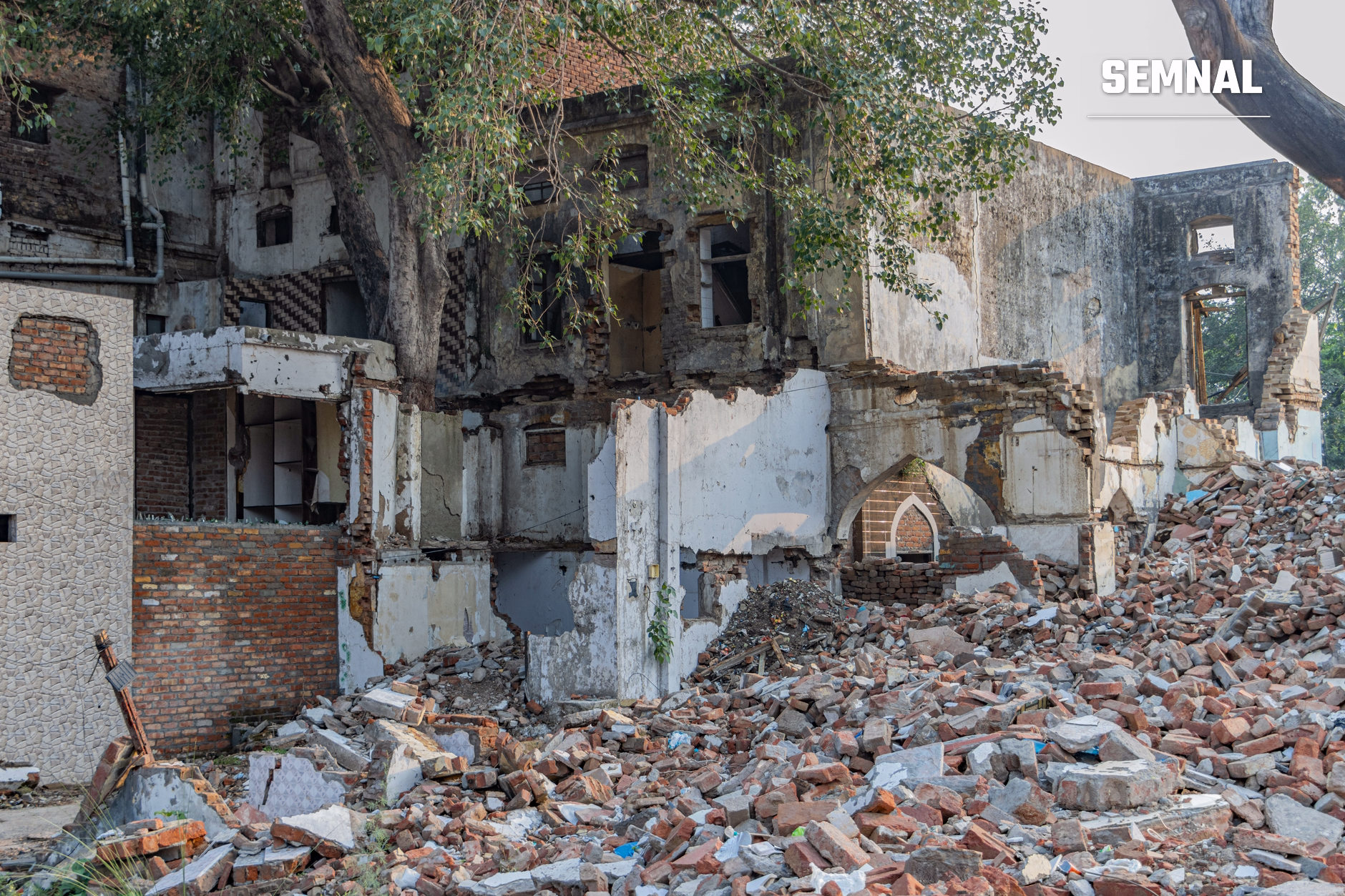 Clădiri distruse și moloz din cărămidă roșie și beton rămas după raiduri aeriene, cu pereți prăbușiți și vegetație pe structurile abandonate în zona unui conflict armat. (Foto: Shantum Singh / Pexels)