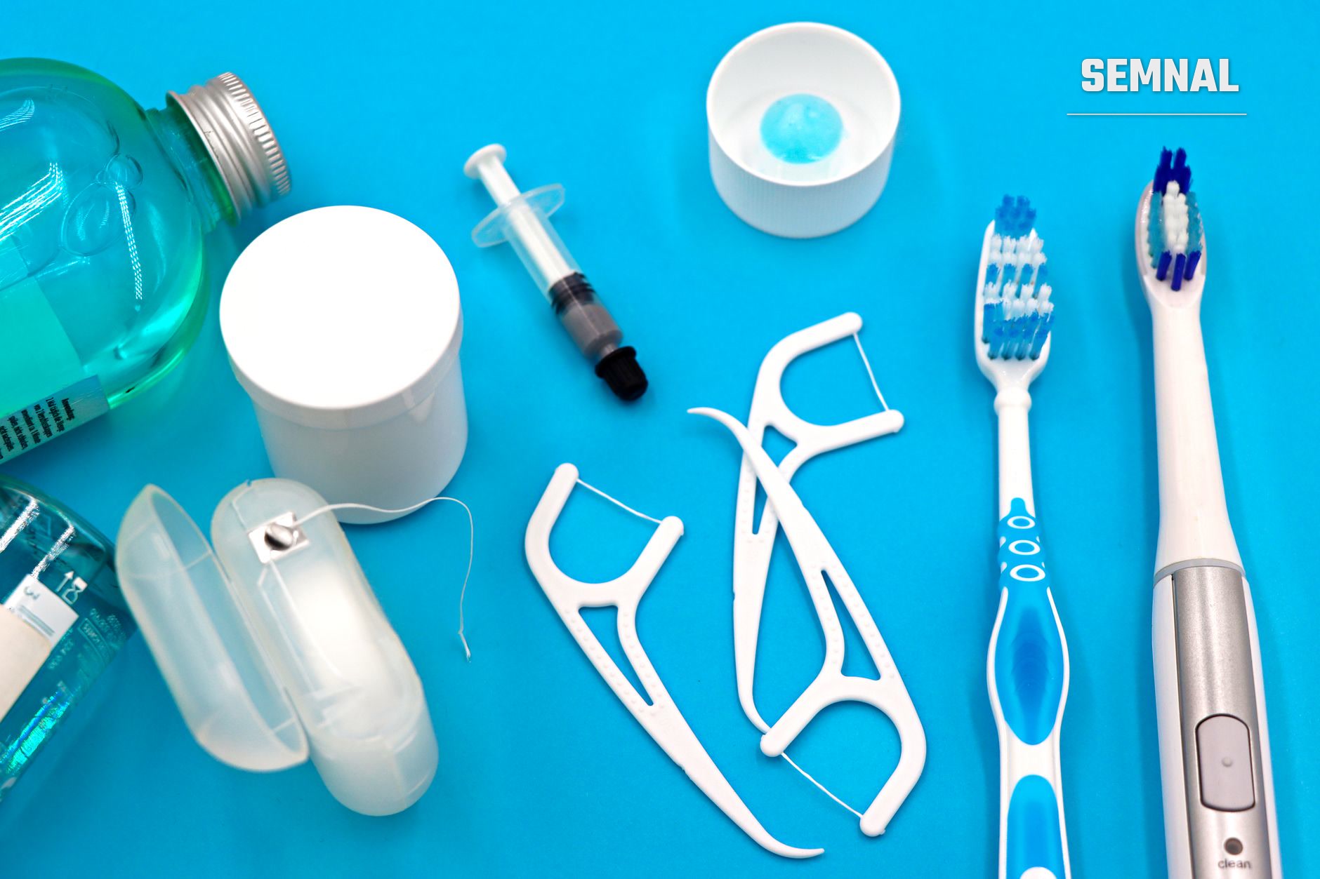 Set complet de igienă orală pe fond albastru: periuțe de dinți, ață dentară, apă de gură și instrumente de curățare dentară (Foto: Marta Branco / Pexels)
