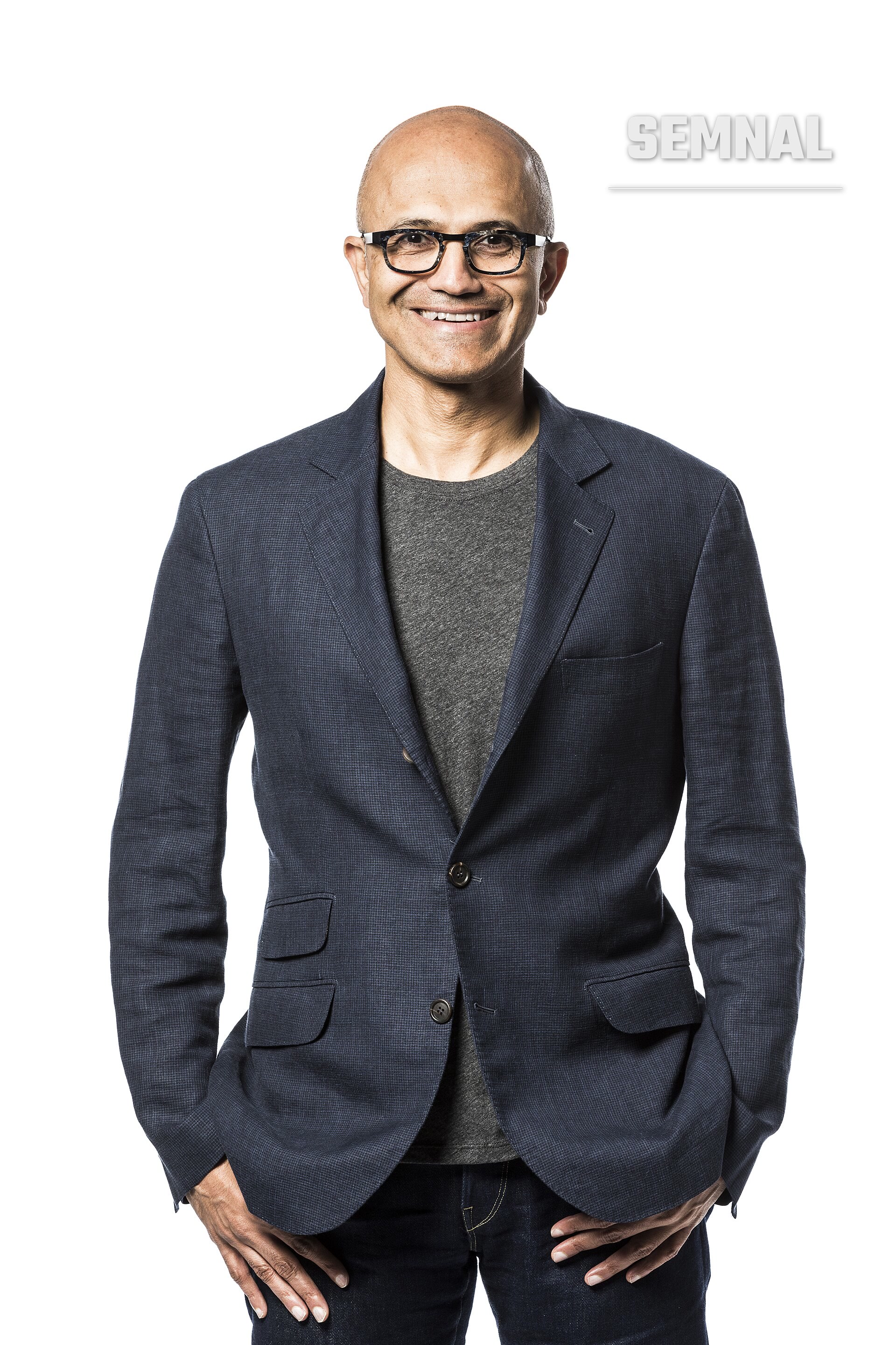Satya Nadella, directorul general, intr-un portret de presa profesional, zambind catre camera, purtan ochelari cu rama neagra si blazer albastru. (Foto: Brian Smale and Microsoft)