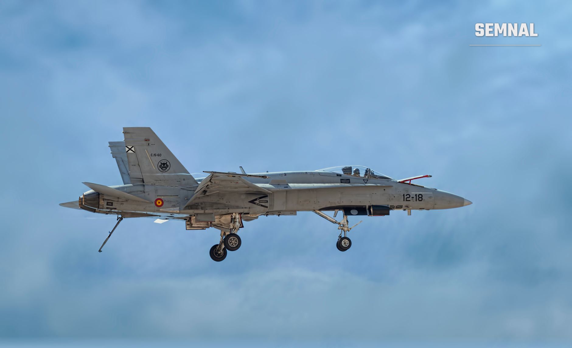 Avion de luptă F/A-18 Hornet spaniol în zbor, cu trenul de aterizare coborât, pe fundal de cer albastru cu nori (Foto: Jesús Esteban San José / Pexels)
