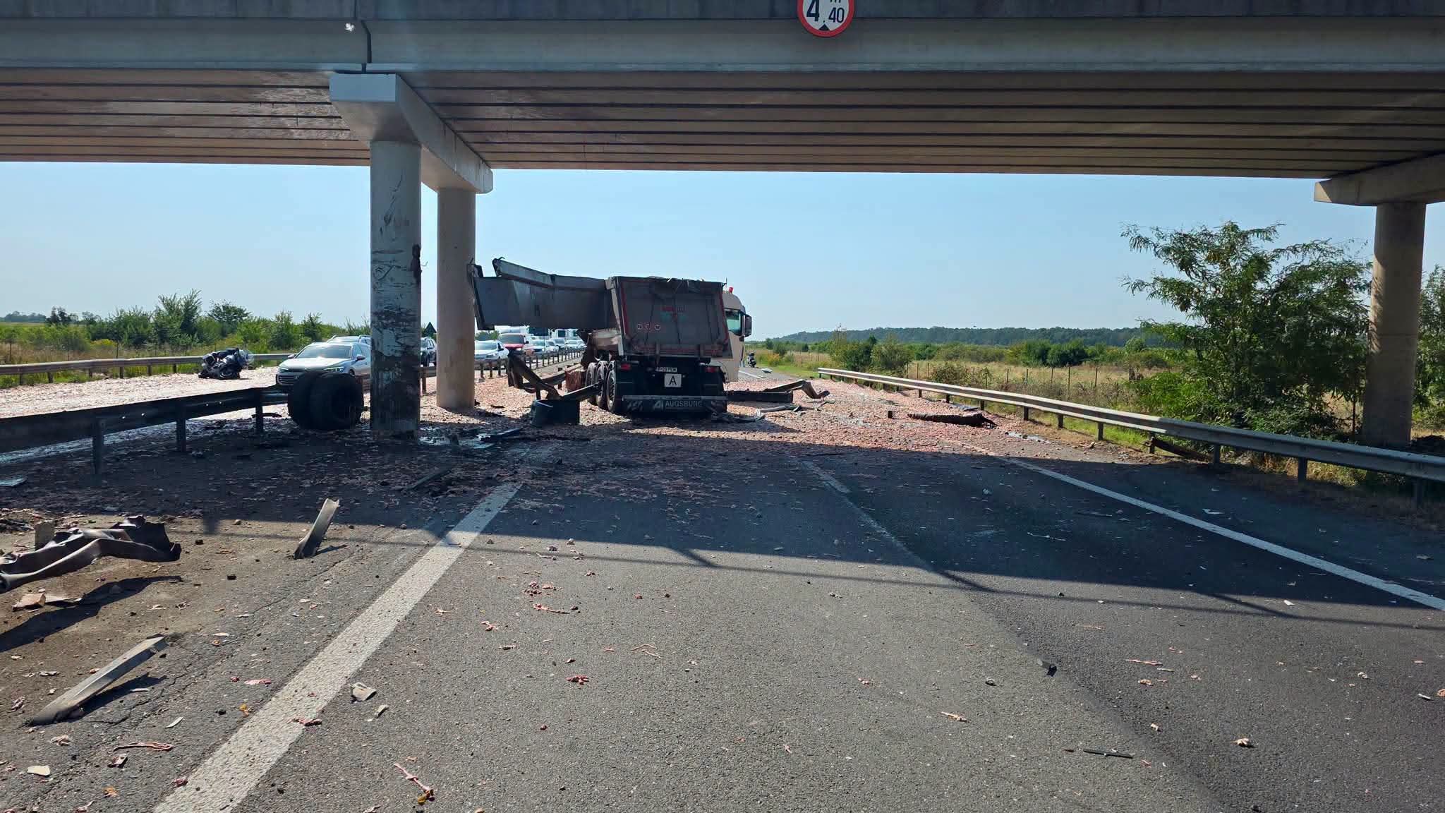 Semiremorcă basculantă oprită sub un pasaj rutier pe autostrada A1, cu resturi de marfă și bucăți de metal împrăștiate pe carosabil