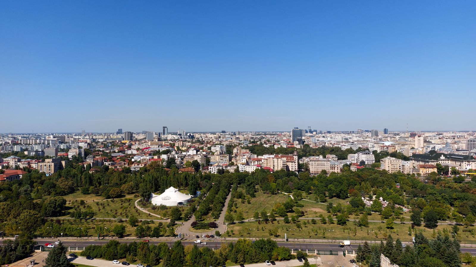 Vedere aeriană a orașului București, cu blocuri și zone verzi, sub cer senin