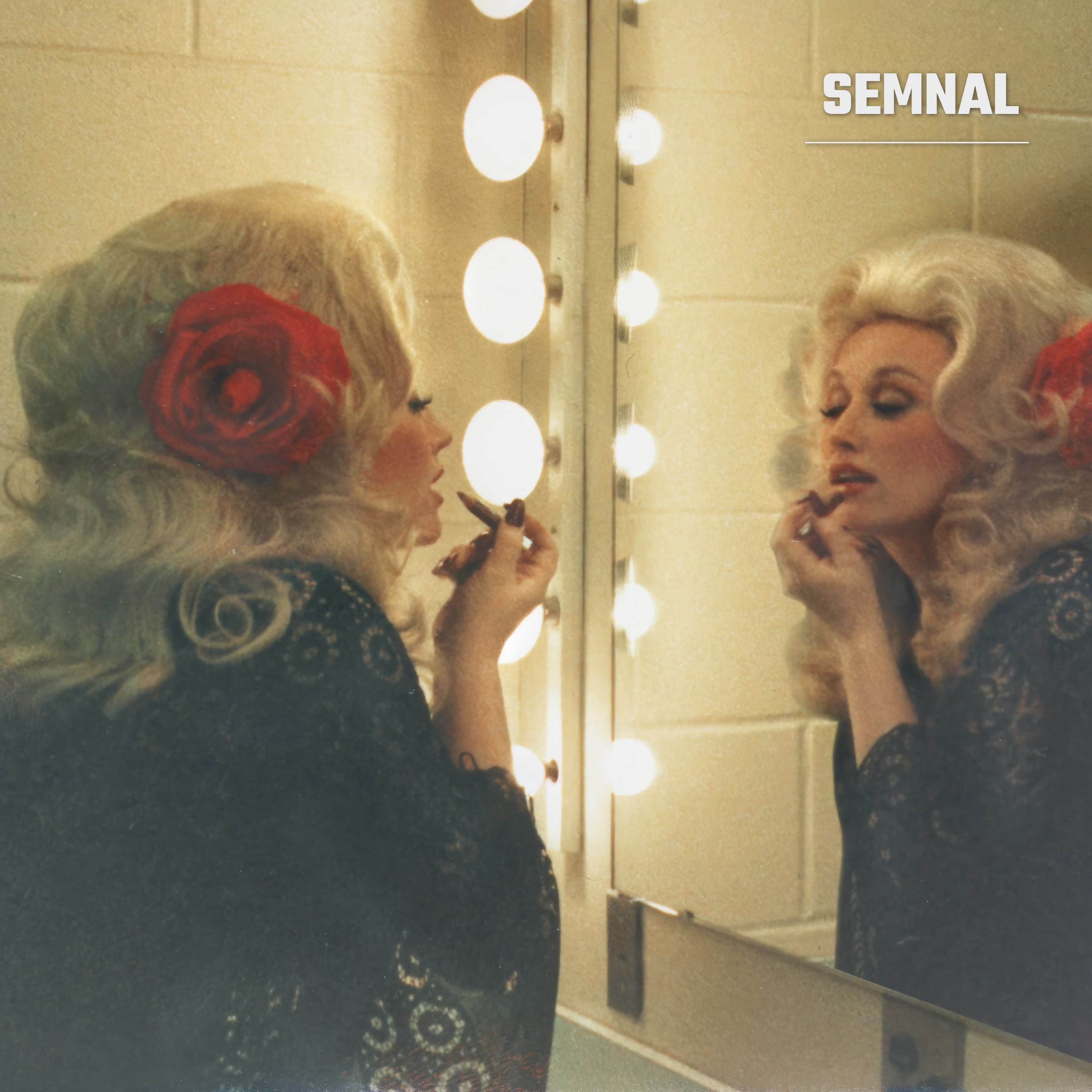 Dolly Parton machiindu-se în fața oglinzii cu becuri dintr-o cabină de artist, cu un trandafir roșu prins în păr