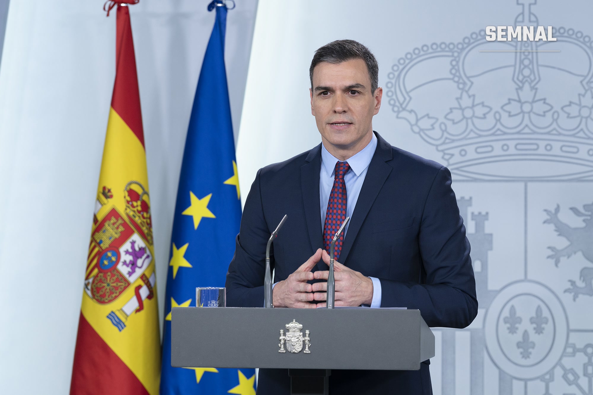 Premierul spaniol Pedro Sánchez vorbind la pupitrul din sala de conferințe de presă a Palatului Moncloa, între drapelele Spaniei și al Uniunii Europene