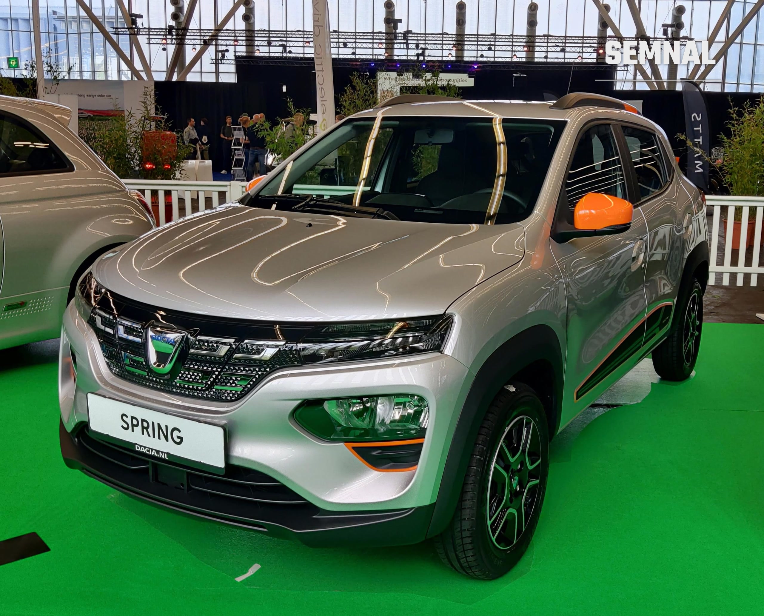 Dacia Spring, generația actuală a mașinii electrice de oraș, în variantă portocaliu cu gri, fotografiată din lateral-față