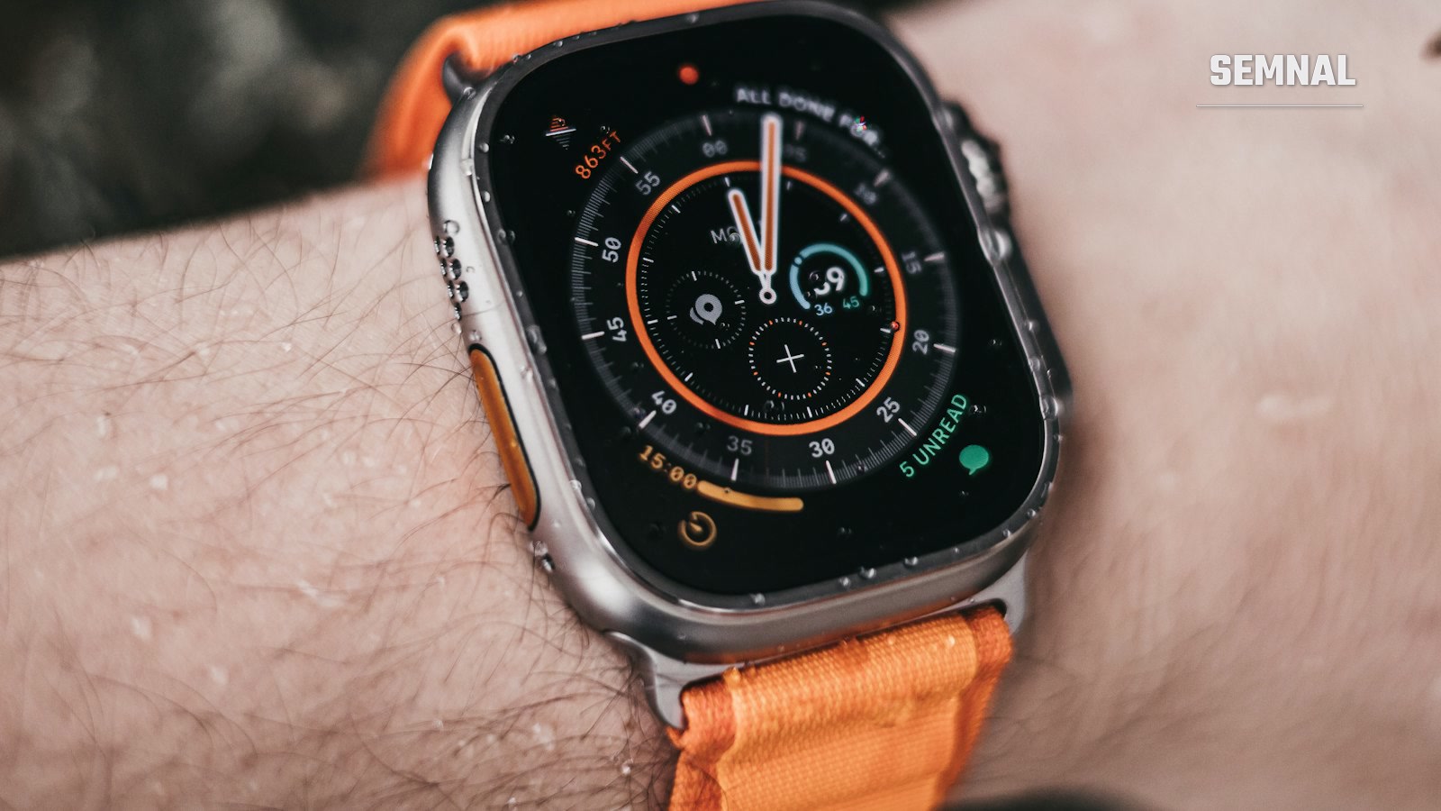 Apple Watch Ultra cu carcasă din titan și curea portocalie, purtat la încheietură în exterior