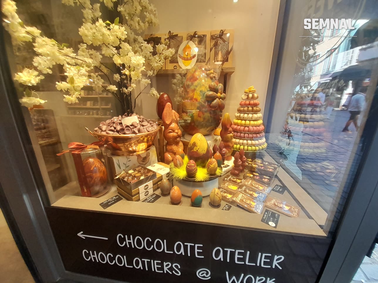 Vitrină „Chocolate Atelier — Chocolatiers @ Work” într-un magazin din Bruges, cu producție vizibilă pentru clienți