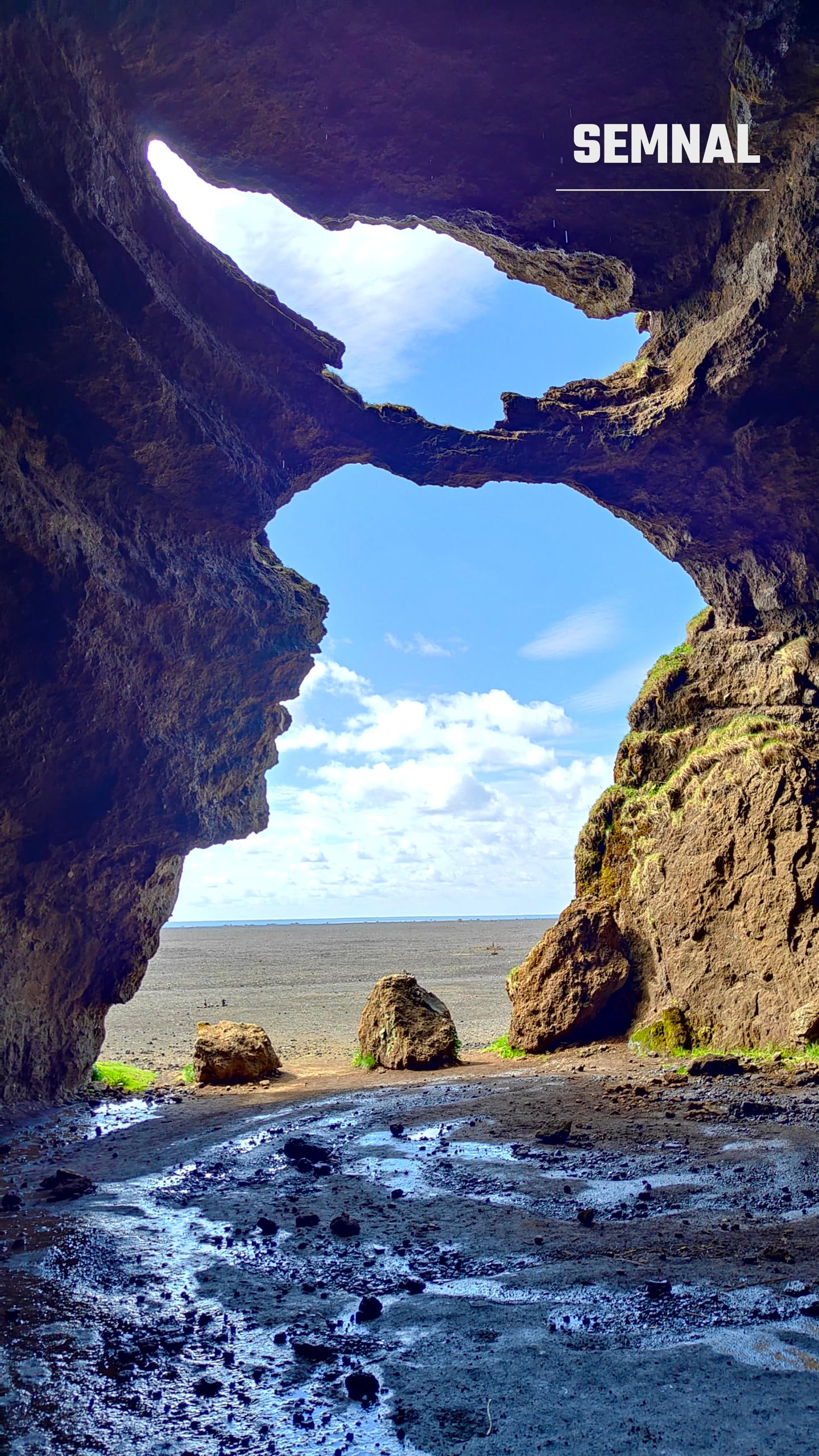 Vedere dintr-o peșteră naturală din Islanda, cu deschideri în formă de arc spre plajă și ocean