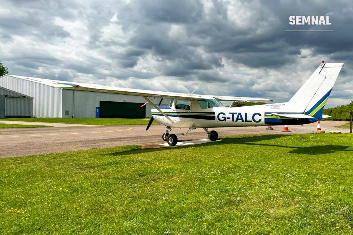 Avion ușor pe iarbă lângă un hangar, imagine ilustrativă
