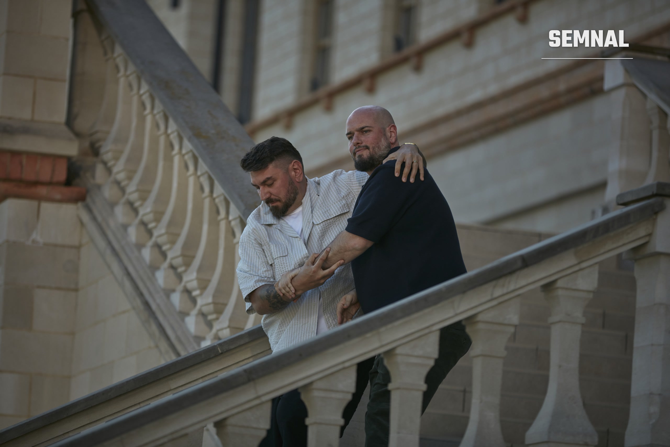 Doi bărbați îmbrățișați coboară scara de piatră a unui castel, într-o scenă din filmul Teambuilding 2