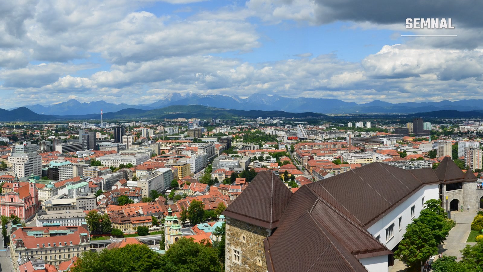 Panoramă a orașului Ljubljana, capitala Sloveniei, văzută de la castel, cu acoperișuri roșii și lanțul muntos în fundal