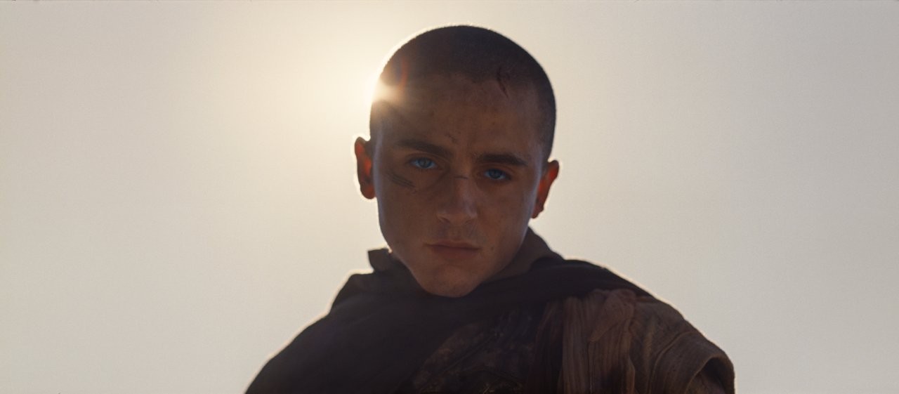 Timothée Chalamet în rolul lui Paul Atreides, cu capul ras și cicatrici pe față, în contralumină în deșert, în „Dune: Partea III”