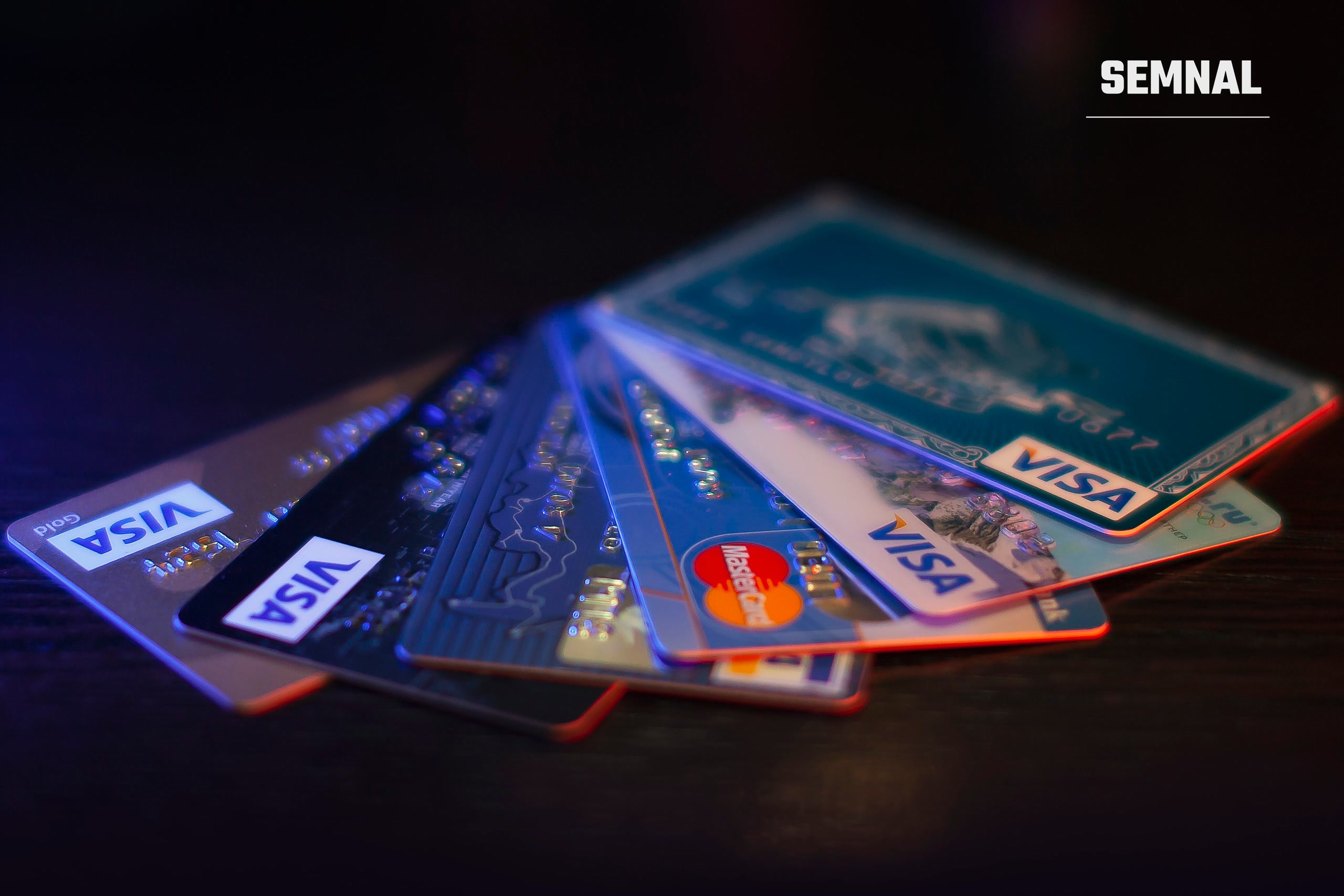 Mai multe carduri bancare Visa și Mastercard așezate în evantai pe o masă întunecată