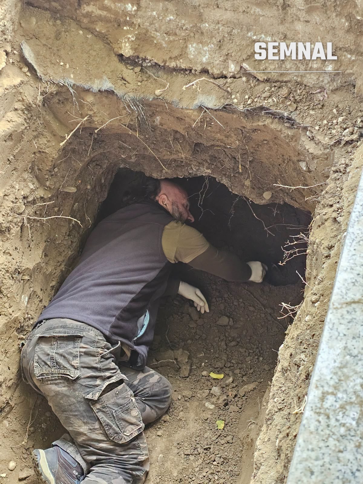 Un membru al echipei cercetează pământul din groapa deschisă în cimitirul din Sighetu Marmației