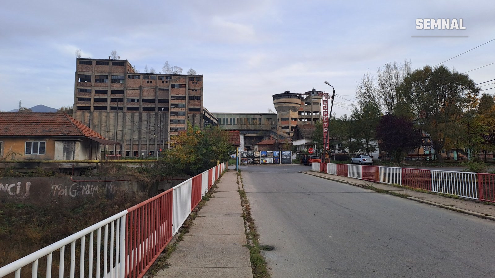 Clădiri industriale din cărămidă ale fostei mine Petrila, cu turnuri de apă în fundal, văzute de pe un pod rutier din orașul Petrila, județul Hunedoara