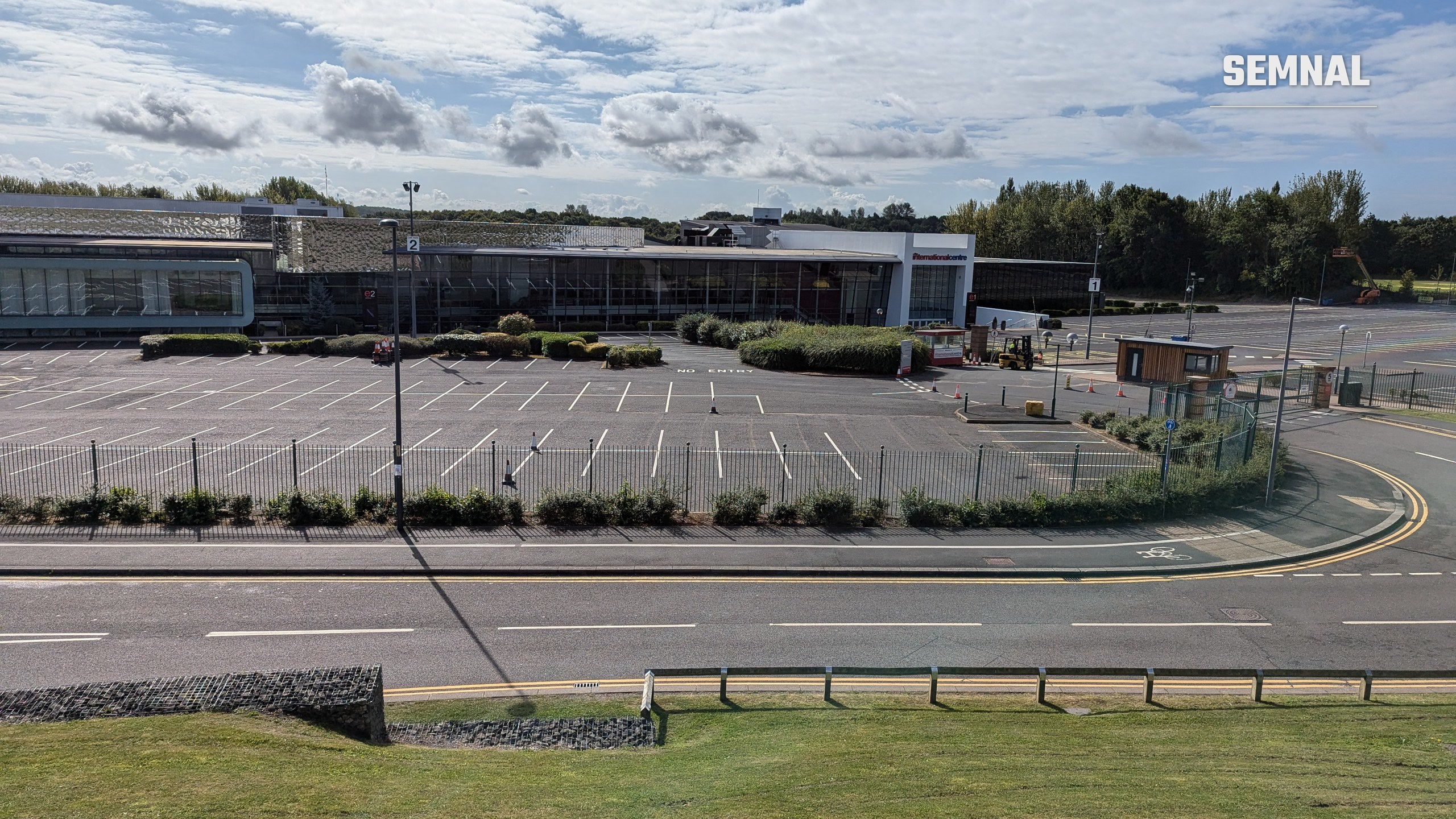 Clădirea Telford International Centre din Anglia, văzută de peste drum, cu parcarea goală în față și cer cu nori
