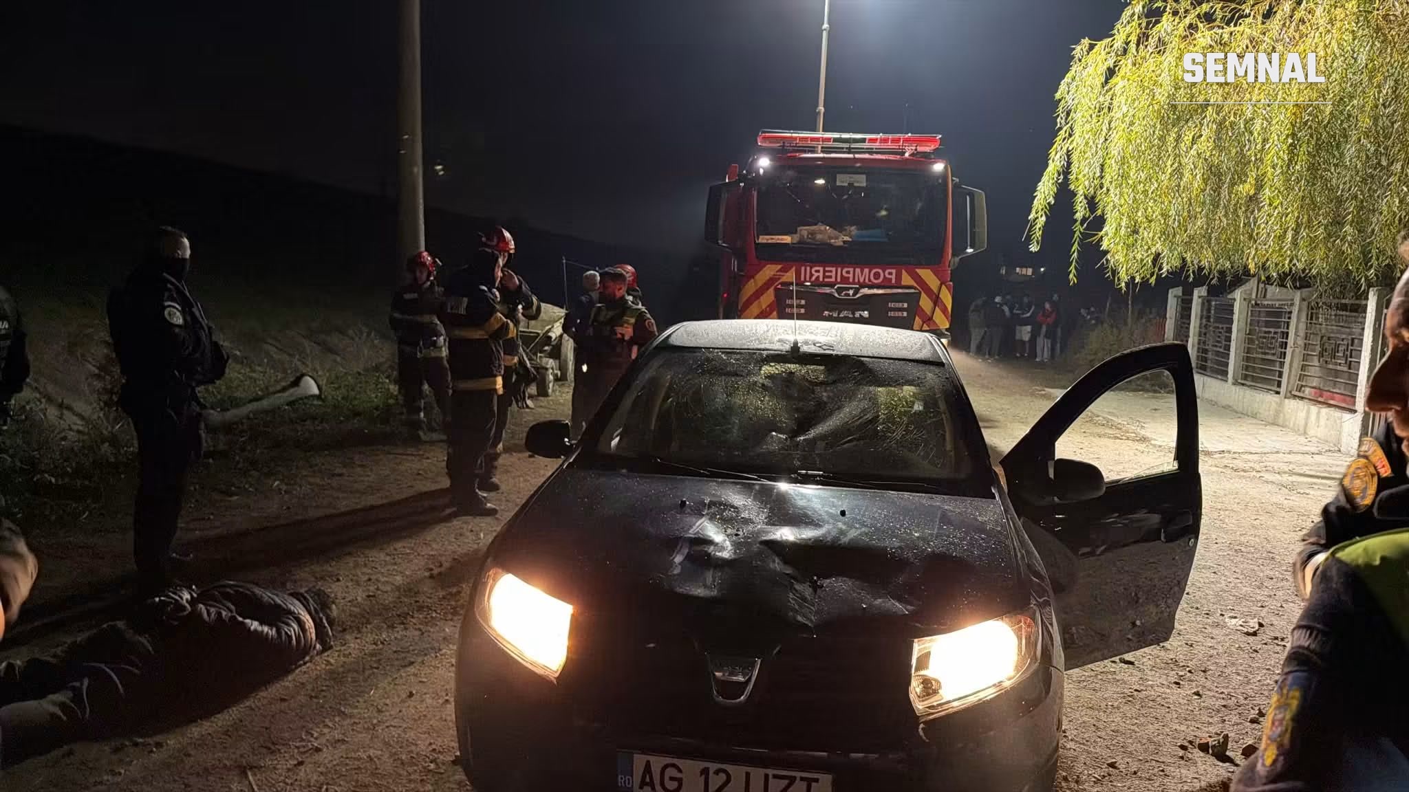 Autoturism cu parbrizul spart și capota deformată, în fața unei autospeciale de pompieri, noaptea, în Ștefănești, Argeș