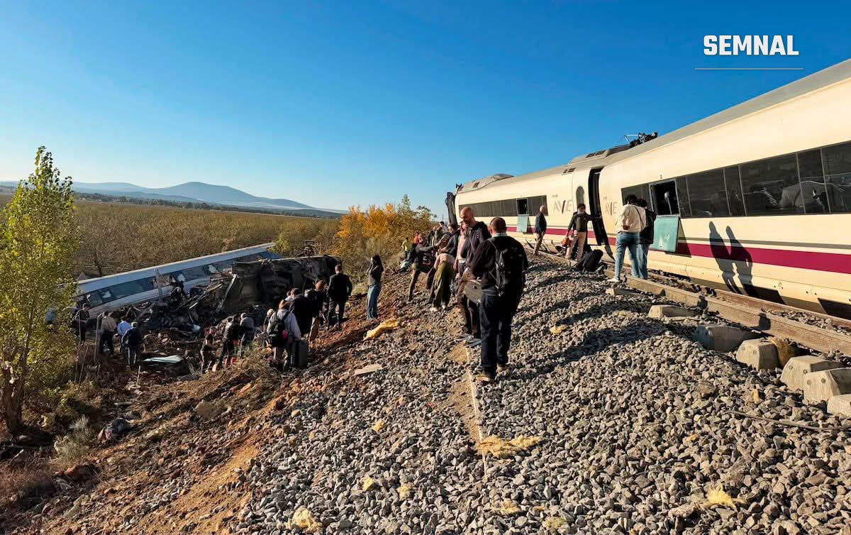Pasageri evacuați merg pe lângă un tren AVE oprit, în timp ce în stânga se văd vagoanele căzute pe taluz, lângă Urda (Toledo)