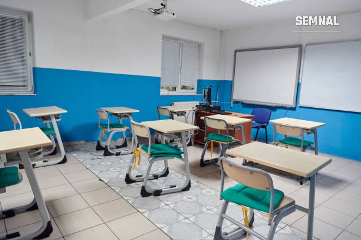 Sala de clasă fără elevi, doar cu banci, scaune și tabla goală.